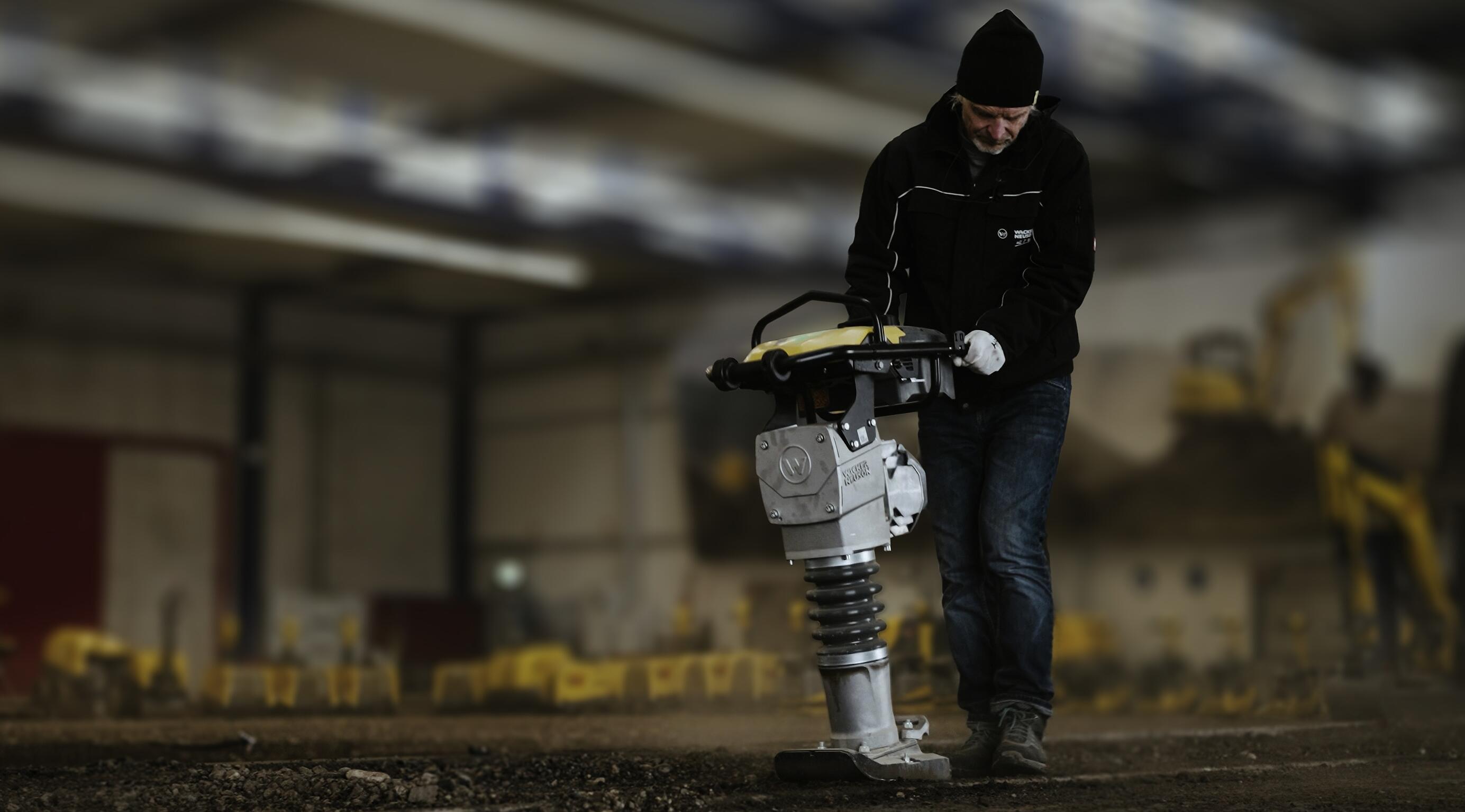 Arbeiter, der einen Stampfer zur Bodenverdichtung in einer Schulungsumgebung für den Innenausbau bedient