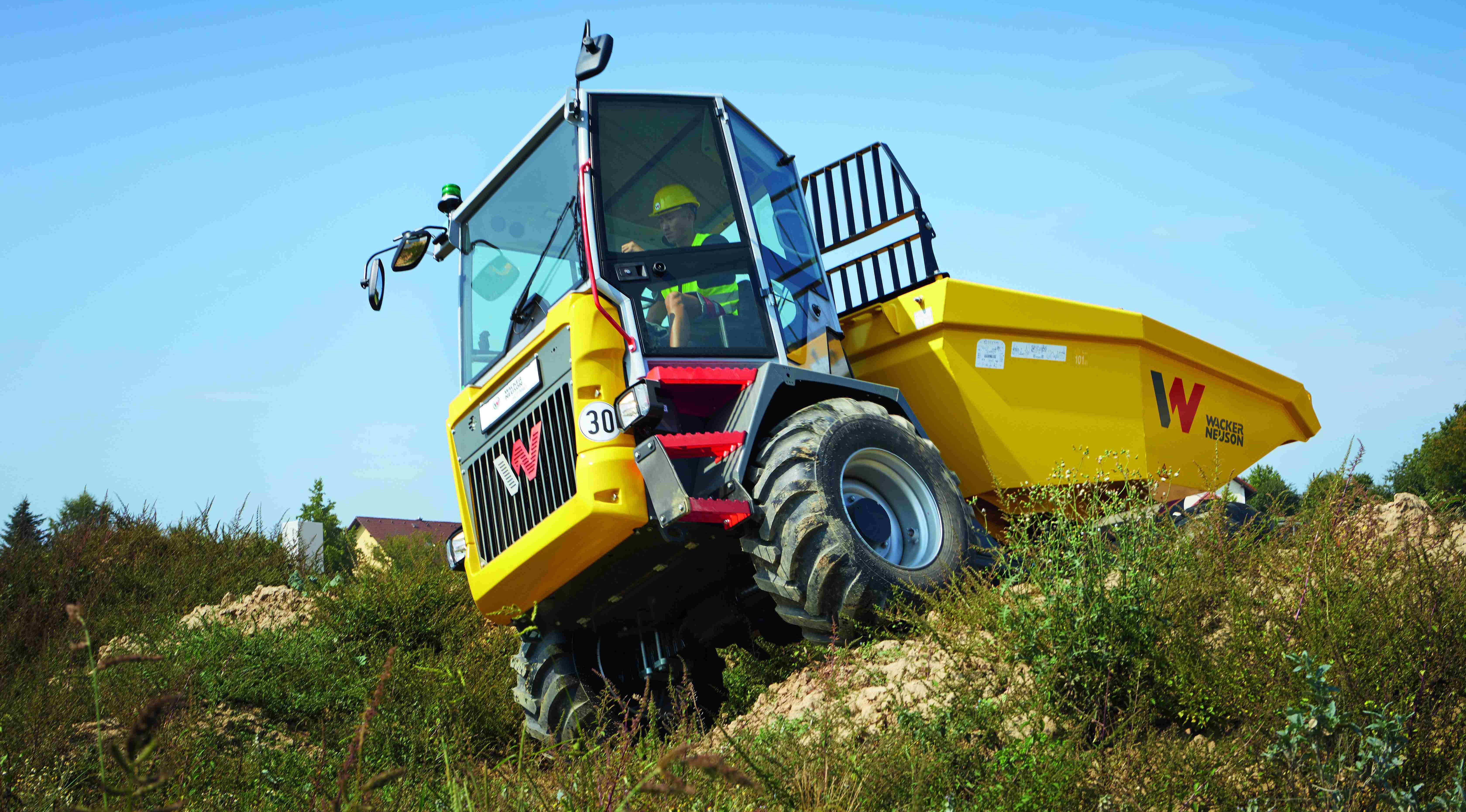 Een Wacker Neuson-kipwagen rijdt over oneffen terrein met een machinist in de cabine tijdens bouwwerkzaamheden