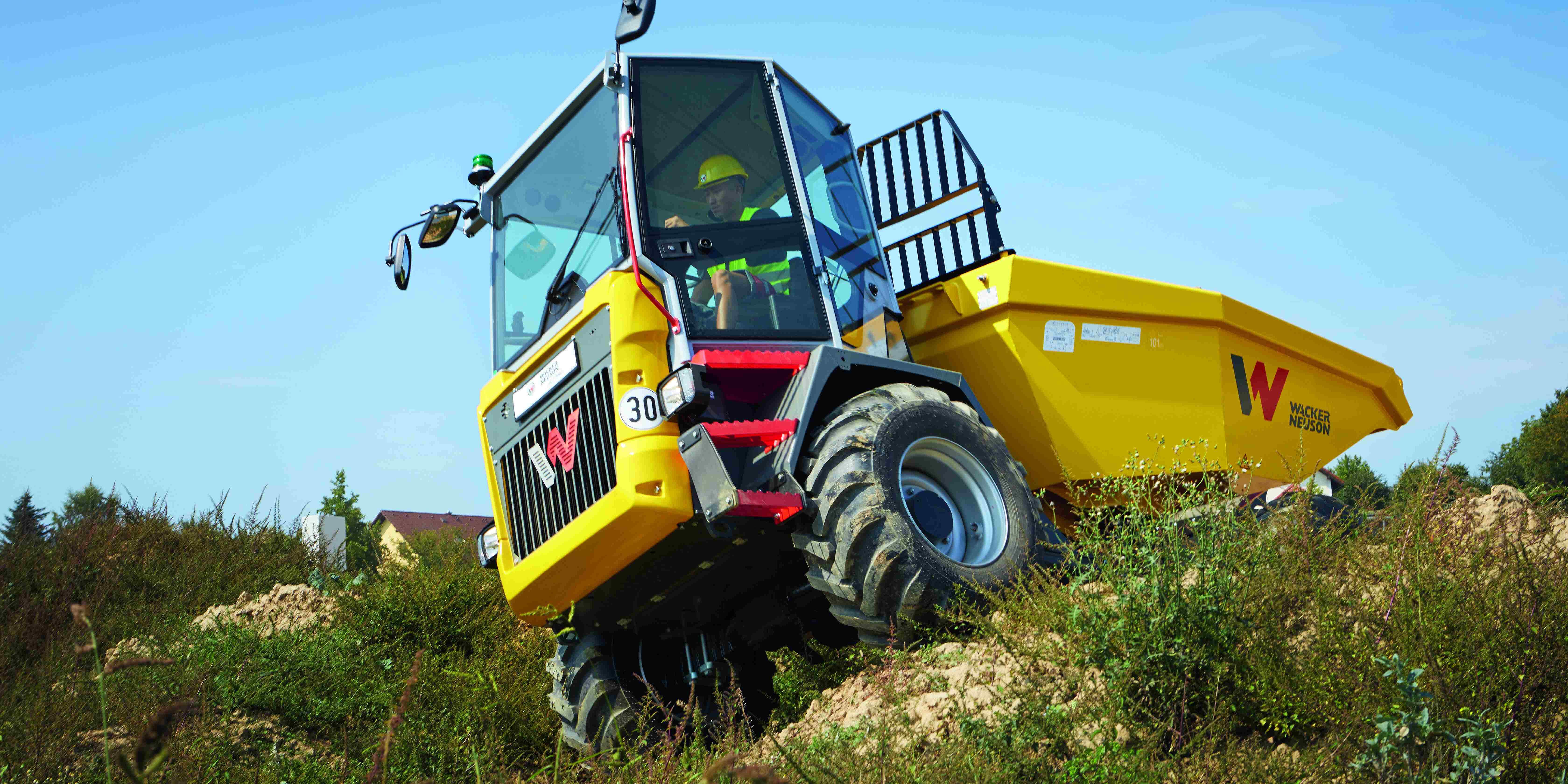 Wacker Neuson dumper driving on uneven terrain with operator in cab during construction work
