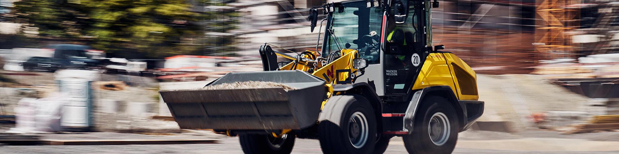 De krachtige Wacker Neuson WL950p-wiellader rijdt op hoge snelheid over een bouwterrein.