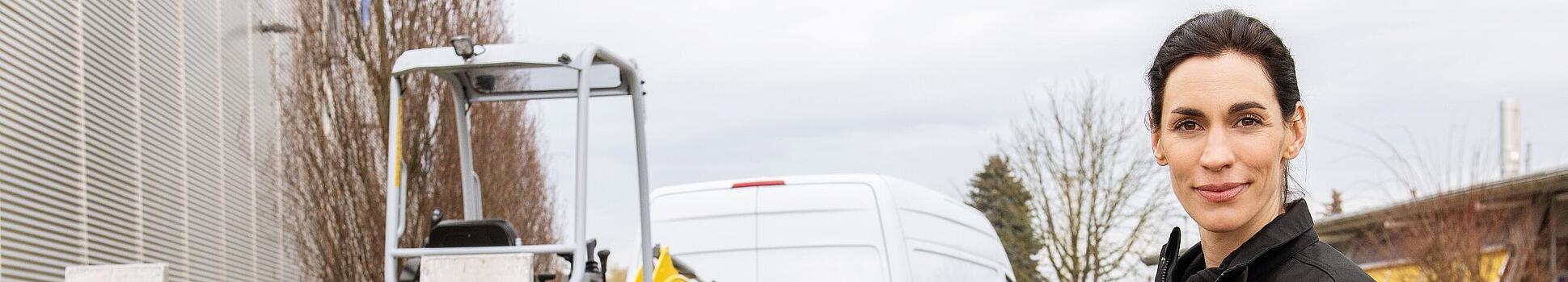 At a Wacker Neuson rental station, an employee stands in front of rented Wacker Neuson tracked excavator on a trailer.