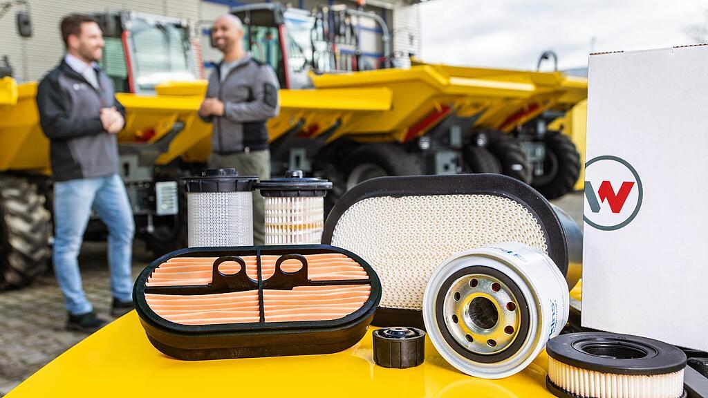 Wacker Neuson-reserveonderdelen op Wacker Neuson-bouwmachines, adviseur van Wacker Neuson, klant en bouwmachines op de achtergrond.