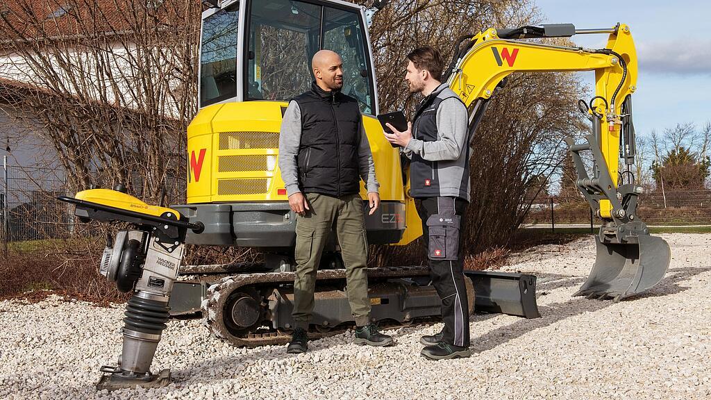 Wacker Neuson Mitarbeiter berät Kunden über das WeCare Paket vor Wacker Neuson Baumaschinen.